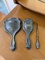 Top view showing the hand mirror, brush, and button hook together on a wooden surface.