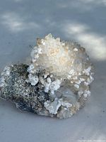 Front view of the mineral specimen showing argentite ore base and clear white crystal clusters