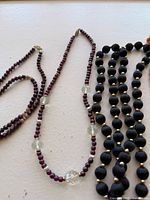Three vintage beaded necklaces laid out, showing detail of beads and clasps.
