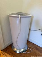 Full view of Brookstone towel warmer, white cylindrical body with chrome base and power cord.