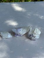 Three calcite with fluorite mineral specimens arranged side by side on flat surface with light and shadow effects.