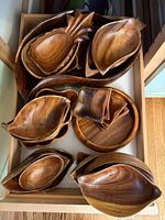 Top-down view of multiple wooden carved bowls showing different shapes including pineapple and leaf shapes.