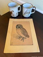 Photo showing two vintage owl mugs and a detailed owl sketch on aged paper placed on a dark surface