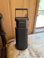 OTTLITE lamp folded with handle upright, showing the ribbed black body and OTTLITE branding on the top part.