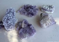 Top-angle photo showing six amethyst crystal clusters arranged on a flat surface in natural light.