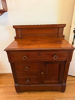 Full front view of Victorian Eastlake washstand cabinet dresser chest, showing drawer, cabinet door, and carved backsplash.