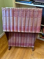 Full set of 20 hardcover vintage encyclopedias arranged upright on a stand showing spine designs and wear.