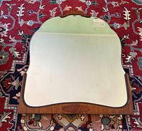 Full view of the wooden framed Art Deco mirror placed on a patterned carpet.