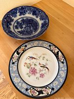Full view of decorative Bird of Paradise plate and blue transferware bowl displayed on a wooden surface.