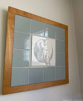 Square wooden frame with a centered ceramic heron tile surrounded by blue tiles.