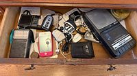 Drawer containing vintage electronics including Motorola radio, iPhone, cassette recorder and accessories