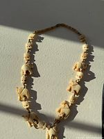 Full view of the vintage elephant bead necklace laid out flat, showing the full length with detailed elephant carvings and small round beads.