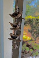 Full view of the ceramic wind chime hanging, showing three birds on driftwood and ceramic beads.