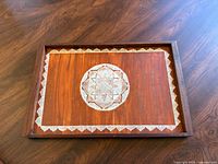 Wooden serving tray viewed from above showing central etched star design and decorative border inlay on the tray surface.
