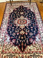 Full view of the rectangular vintage medallion rug on hardwood floor showing the central medallion design with floral motifs and patterned border.