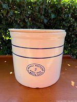 Front view of 2 gallon Miali Pottery crock showing blue lined cream ceramic body with signature stamp