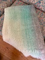 Folded vintage mohair throw showing gradient colors and texture, laid on patterned fabric background.
