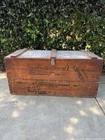 Side view of vintage wooden crate showing military markings and stencil text.