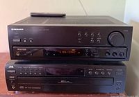 Front view of the Pioneer VSX-40c stereo receiver showing control buttons, volume knob, LED display tuned to FM 106.1 MHz, and headphone jack, placed on top of the JVC CD changer unit.