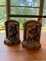 Front view of the pair of bookends showing sitting thinker sculpture on an arched decorative base