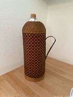 Front view of vintage bottle with woven wicker sleeve and cork stopper