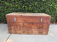 Front and side view of vintage wooden naval crate against hedge background showing metal latches and wood grain
