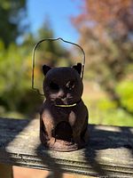 Front view of the rustic black cat lantern with metal wire handle visible, showing details of the cat's face and body.