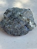 First image showing a rough, metallic silver-gray zinc-lead ore rock specimen with coarse-grained texture and uneven surface.