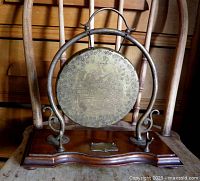 Front view of brass gong on wood stand