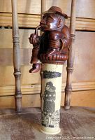 Full view of tobacco container showing carved resin figure lid seated on etched bone cylinder