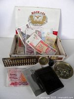 Open cigar box with banknotes, abacus, coin dish, wallet, ink bottle and photo