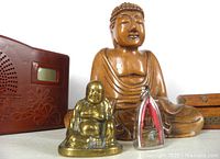Group shot showing wood Buddha statue, brass figurine, cased pendant, chanting radio, corner of wood box