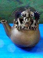 Front view of welded metal teapot sculpture with creature