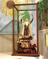 Front view of wax sculpture in display case, showing robed figure and altar scene