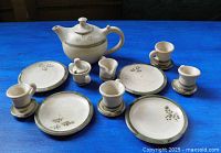 Full set on blue surface showing teapot, cups, saucers, creamer