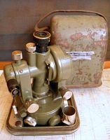 Theodolite on base next to original carry case