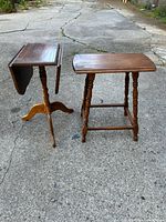Two small wooden tables standing on pavement