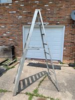 Full view of aluminum step ladder opened on driveway