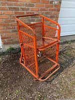 Full view of orange metal beer cart against brick wall