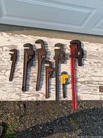 Seven pipe wrenches laid out in size order