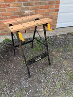 Full view of stand assembled showing wooden jaws, yellow handles, metal frame.