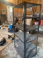 Full view of steel shelving unit showing five shelves and perforated frame