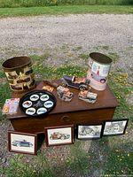 Group shot of entire lot on wooden chest with wastebaskets, tray, coasters, model cars, framed prints and card packs