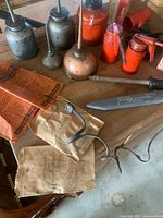 Group of oil cans, file, punch, envelopes and cable on table