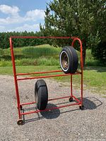 Full view of red tubular steel tire display rack holding two sample tires