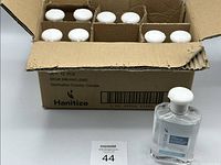 Open shipping box showing multiple white-capped sanitizer bottles plus one bottle in front