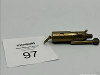 Full view of brass trench lighter with auction tag