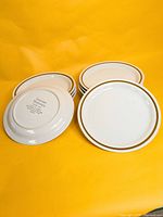 Stack of eleven stoneware plates, one inverted showing backstamp.