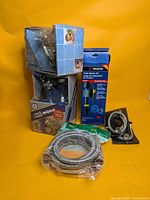 Group shot of all plumbing items: two Moen faucet boxes, Moen toilet repair kit packaging, braided supply hoses