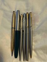 Six pens laid side by side showing finishes and clips